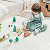 A young girl sits on the floor, happily playing with colorful toys scattered around her.