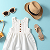 Summer clothes and accessories displayed on a vibrant blue background, showcasing a seasonal fashion theme.